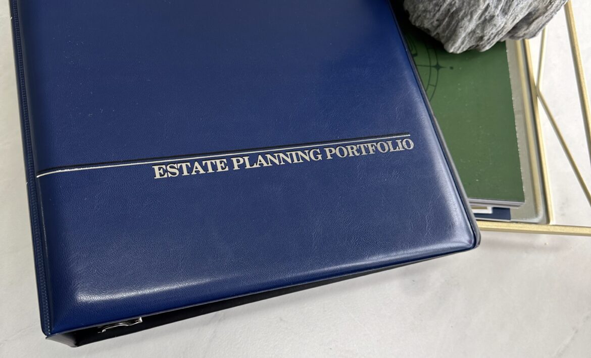 Blue leather estate planning portfolio binder placed on a marble surface beside a small Buddha statue and a gold tray